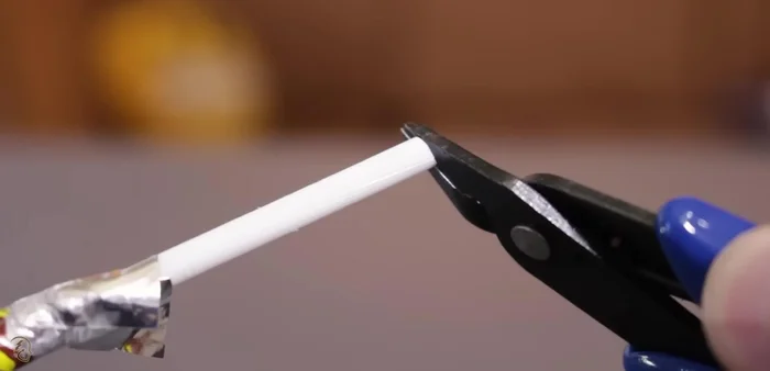 Crear un pequeño gancho con otro alambre, cruzarlo y hacer un doblez para que no se salga. Fijar con silicona caliente.