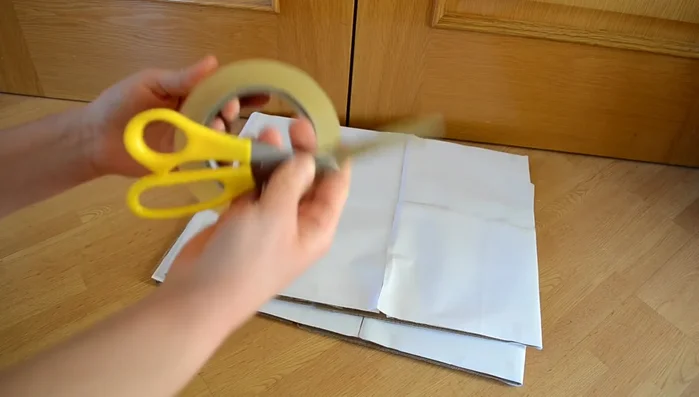 Une las cajas: Coloca las cajas juntas y pégalas por el centro con cinta adhesiva. Es más fácil hacerlo con las cajas tumbadas.