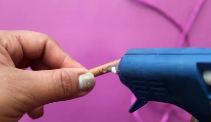 Decorar la base: Aplica silicón y pega las hojitas decorativas para que queden bien sujetas.