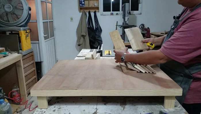 Forrar los lados y la parte trasera de la base con piezas de madera más pequeñas, creando un diseño en forma de 'U'. Utilizar pegamento y pistola de clavos.