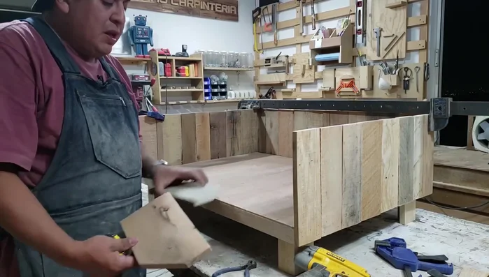 Cortar dos piezas de madera más anchas (13cm) con cortes en ángulo de 45 grados para la entrada de la cama. Pegarlas para terminar de cerrar el frente.