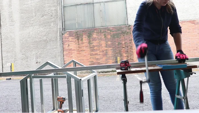Instalar la pieza de canal para el cerramiento de la puerta, doblando las pestañas para fijarla a los postes.