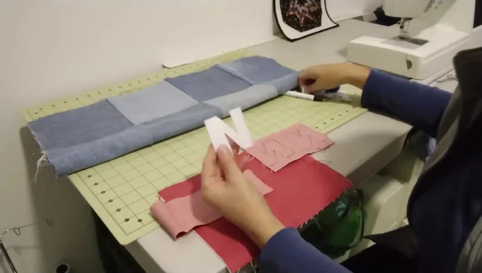 Aplicación de las letras: Crear letras con el nombre de la mascota en tela de mezclilla de un color contrastante, fijarlas al patchwork con puntada zigzag para asegurarlas.