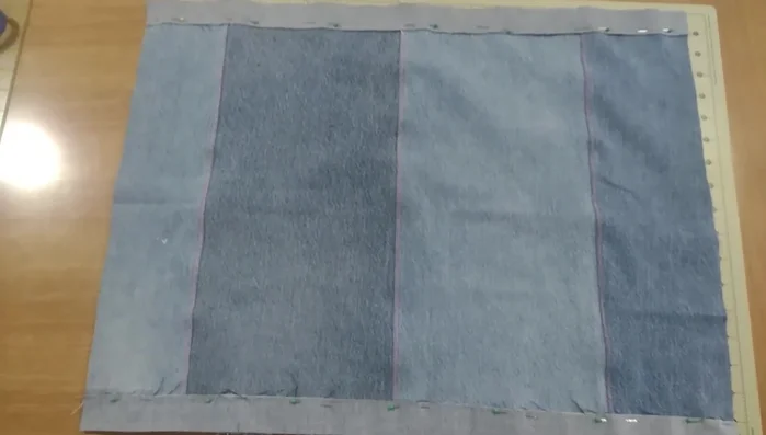 Creación de la parte trasera: Cortar tiras de mezclilla y unirlas para la parte trasera de la almohada, utilizando puntada zigzag para evitar el deshilachado y darle un acabado plano.