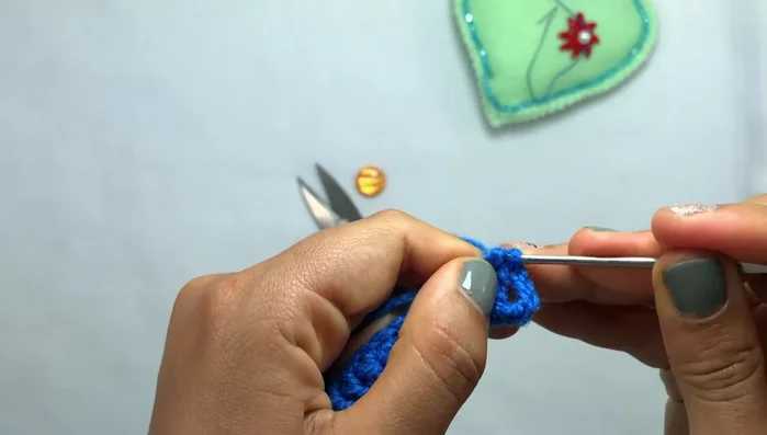 Introducir la aguja en el hueco de la esquina, pasar el hilo y cerrar el punto.