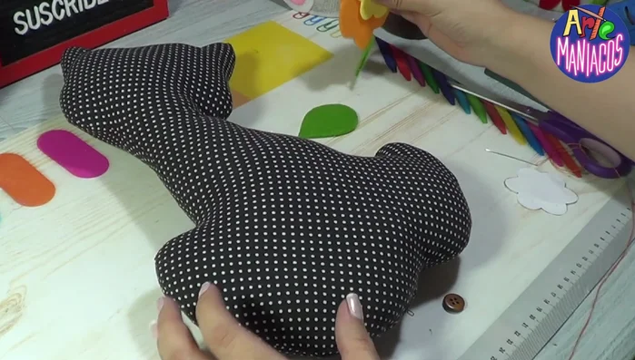 Pegar los ojos: Pegar los ojos plásticos (opcional) sobre una base de fieltro blanco para que resalten sobre la tela negra.