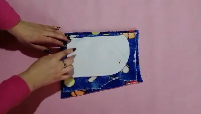 Cortar y coser la capucha: Colocar el patrón de la capucha sobre la tela, asegurar con alfileres y recortar, dejando un pequeño margen para la costura en la parte redondeada. Coser y realizar una costura en zigzag para reforzar.