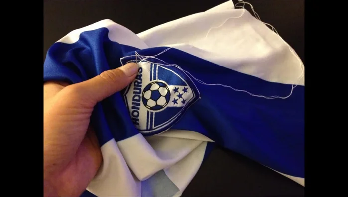 Voltear la camiseta. Pegar o coser el símbolo de Honduras a la camiseta (el video utiliza puntadas).