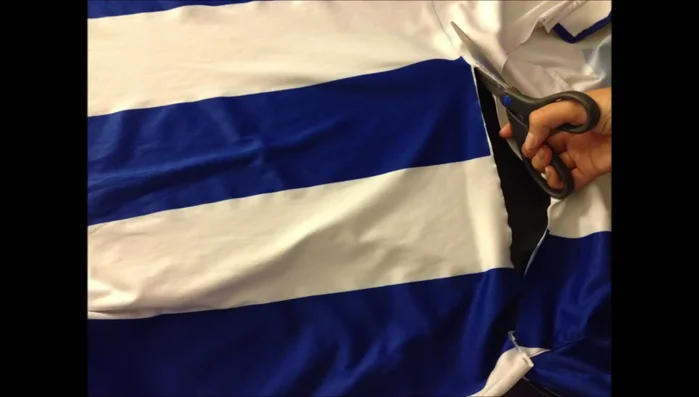 Colocar la camiseta sobre una mesa y cortar los lados derecho e izquierdo, dejando dos pedazos de tela.