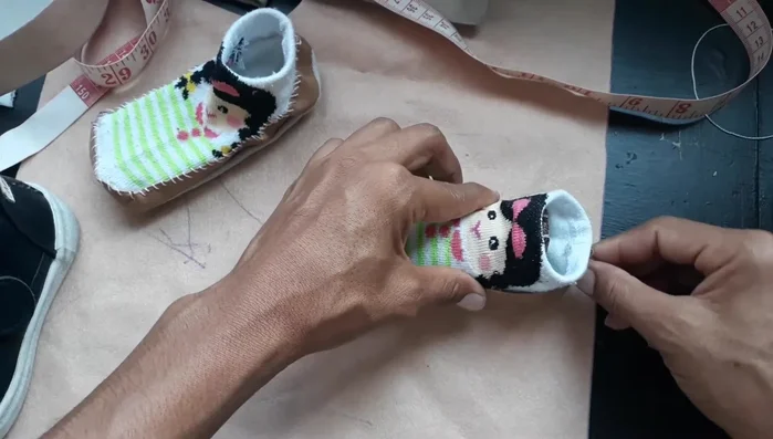 Coser la tira al calcetín del bebé alrededor del borde. Se puede usar hilo normal o hilo de zapatero para mejor estética.