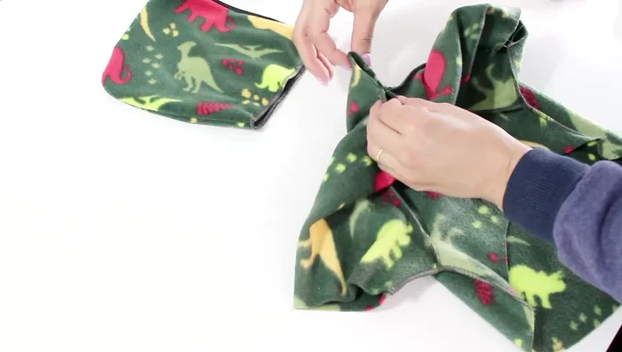 Unión de la capucha a la prenda: Centra la capucha en la parte posterior del cuello, uniendo la costura central de la capucha con la costura central de la espalda de la prenda. Cose alrededor de todo el cuello.