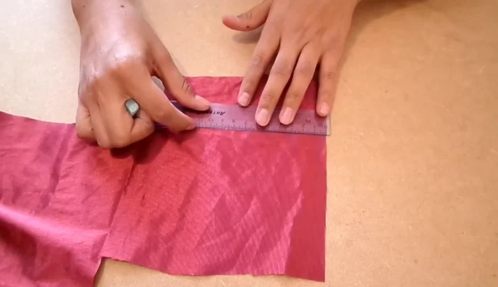 Seguir el contorno de un óvalo con la tela para medir la longitud necesaria para las tiras. Señalar con tiza, dejando 0.5 cm extra. Recortar cuatro tiras de 3 cm de ancho.