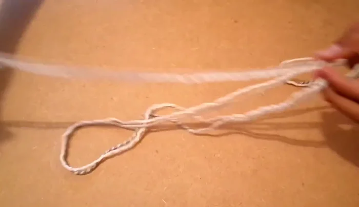 Preparar los cordones (80 cm). Doblar por la mitad, enrollar y unir los dos extremos. Hacer un nudo y apretar. Pasar el cordón por el orificio del zapatito con cuidado.