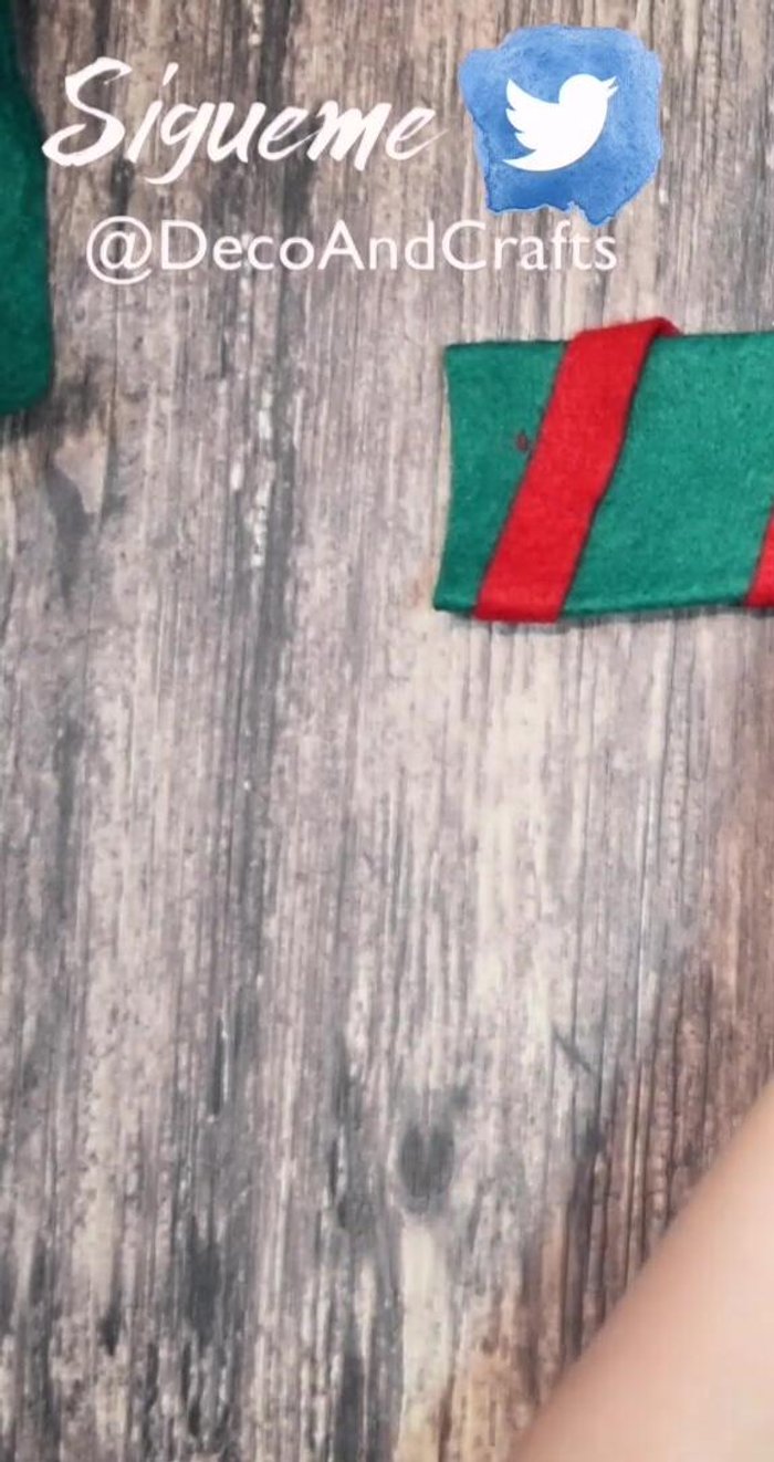 Corta un rectángulo irregular de fieltro verde y pégalo en una orilla de la bufanda; pega tiras rojas.