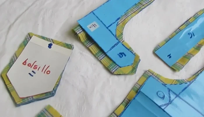 Cortar la tela: dos piezas de cada color para la espalda, dos piezas para el pecho, y dos piezas para los bolsillos, de ambos colores de tela.