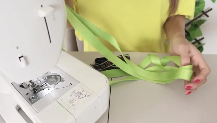 Para la correa, cortar una cinta larga (aprox. 50 cm) y otra cinta decorativa del mismo largo. Unir ambas cintas con silicona o costura (402.29).