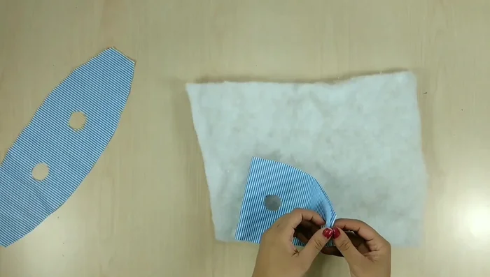 Preparar la guata: Colocar la guata sobre una de las piezas de tela y recortar siguiendo el contorno de la pieza de tela.