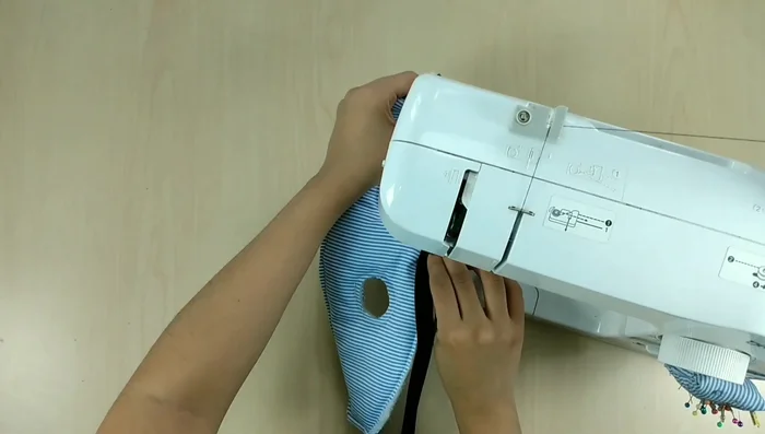 Colocar el bies: Colocar el bies (cinta de tela) alrededor del borde exterior de la pechera. Coser de un lado, doblar y coser por el otro lado (opcionalmente se puede coser a mano para mayor control).