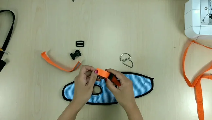 Instalar broches y tiras: Colocar los broches y las tiras para sujetar la pechera al gato. Coser las tiras y los broches firmemente.