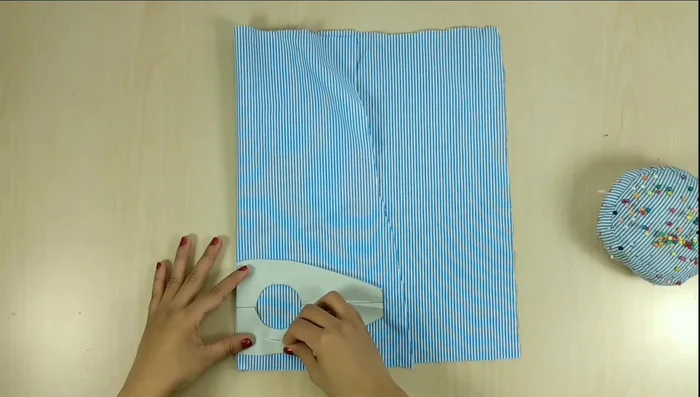 Cortar las piezas: Doblar la tela a la mitad, colocar el molde y asegurar con alfileres. Marcar 1 cm de margen de costura alrededor del molde, incluyendo el círculo interior, y cortar dos piezas iguales.