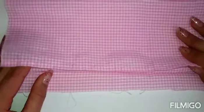 Doblar la tela y colocar el molde: Dobla la tela por la mitad y coloca el molde sobre ella, sujetándolo con alfileres.