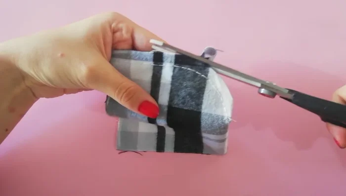 Cortar y rematar la capucha: Cortar el exceso de tela dejando 1 cm. Aplicar pespunte y hacer una basta en el borde.