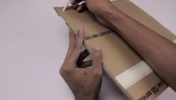 Hacer un orificio en cada esquina para los palos de madera.