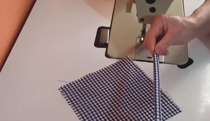 Coser las tres partes (las dos tiras y el cuadrado) juntas.