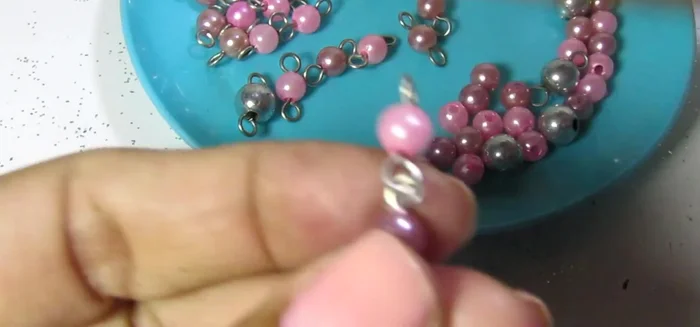 Armar la pieza central: Abrir un aro y agregar dos cristales rosados, cerrar. Repetir con otro aro y dos cristales rosados. Unir ambos aros con una piedra central plateada de 8mm.