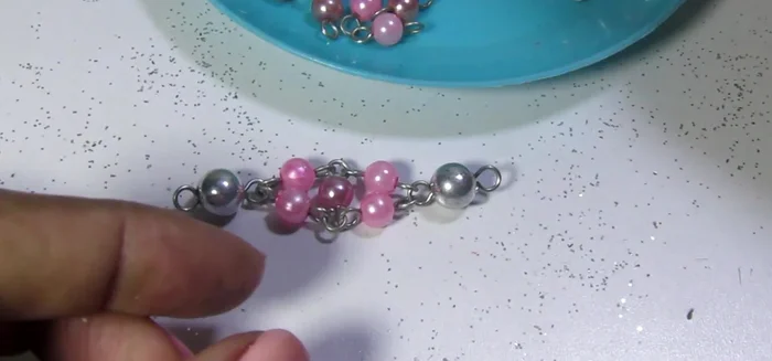 Repetir el proceso creando otra pieza similar, pero invirtiendo los colores (piedra lila central y perlitas rosadas).