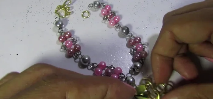 Agregar el dije: Abrir los ganchos del dije y colocarlo en el collar.