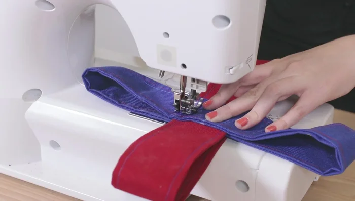 Formar una X y coser el cuadrado reforzado dos o tres veces para mayor resistencia. Usar la manivela para evitar romper la aguja.