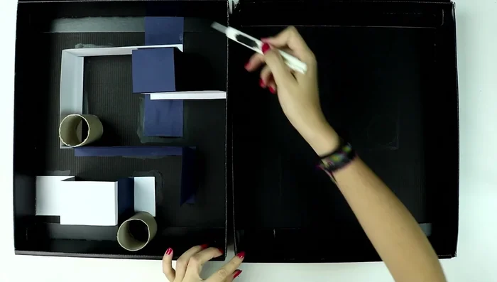 Crear los agujeros: Hacer agujeros en la tapa y la base de la caja con el cúter, donde no haya obstáculos para que la pelota pueda pasar.