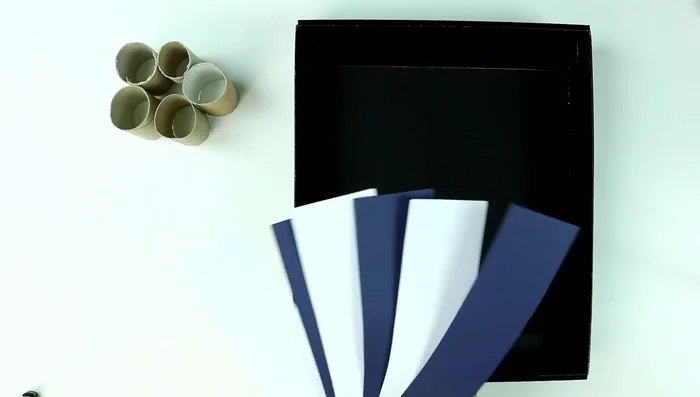 Construcción de puentes y paredes: Cortar tiras de cartulina de la medida de la altura de la caja. Doblarlas para crear puentes y pegarlas a la base de la caja. Crear paredes con las tiras y los rollos como refuerzo. Asegurar que la pelota de ping pong pueda pasar por los agujeros.