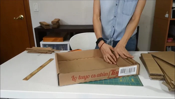 Acomodar y cortar más cartones (opcional): Acomodar las piezas cortadas en la caja para ver cuántos se necesitan. Se puede cortar más cartones del mismo tamaño o de diferentes tamaños para añadir variedad al rascador.