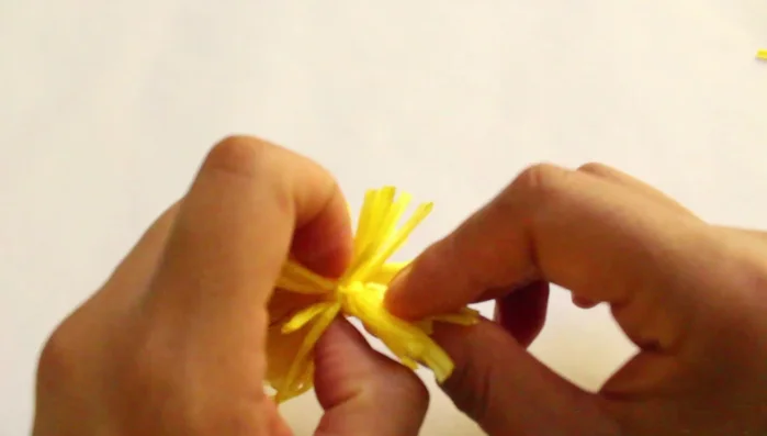 Introducir una aguja en la rafia para hacer el pompón más esponjoso.