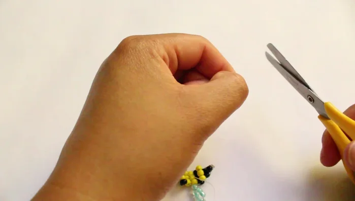 Introducir el hilo de nylon en la abejita y atarlo a un palito.