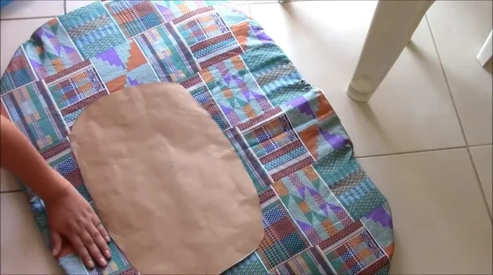 Colocar el molde de papel sobre la pieza cosida y trazar la forma de la base de la cama.