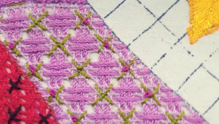 Utilizar un cuarto tono (color fucsia) con hebra sencilla para crear un detalle adicional. Enrollar tres veces y hacer un nudo francés en cada 'tachecito' verde.