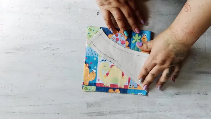 Cortar la tela: Dobla la tela por la mitad y coloca el patrón sobre ella, sujetándolo con alfileres (264.86). Corta dos piezas idénticas.