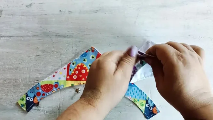 Colocar los broches: Marca la ubicación de los broches (554.22). Dobla los extremos del paliacate y coloca los broches a medio centímetro de la costura (572.83). Si usas broches de coser, haz pequeños agujeros para evitar que la tela se rompa (588.79).