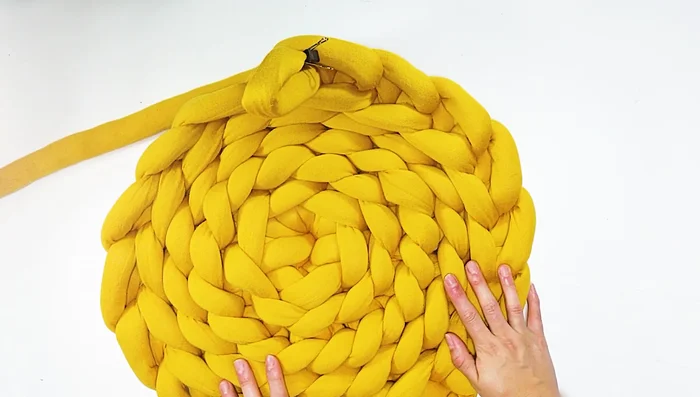 Tejer las paredes: Marcar un punto con un clip. Tejer hacia adentro, jalando el hilo por cada punto y pasando al siguiente. Repetir hasta llegar al clip. Repetir este proceso por tres vueltas para lograr la altura deseada.