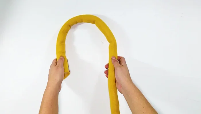 Formar el primer punto: Pasar la punta del hilo por encima formando una 'e', pasar la mano por el agujero y jalar el hilo.