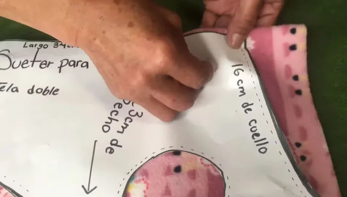 Doblar la tela para la parte del cuello y los brazos, utilizando el molde y alfileres para asegurar la forma.