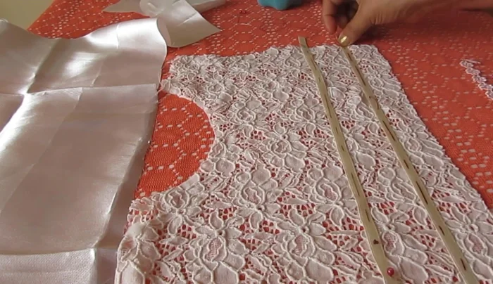 Unir la cinta y la blonda al encaje. Coser las cintas y las blondas al encaje, creando dos filas de cinta con la blonda en el medio. Puedes usar alfileres para sujetar antes de coser.