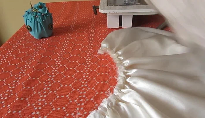 Unir la blusa y la falda. Colocar la falda fruncida (la parte más pequeña) dentro de la blusa, alineando los derechos de ambas telas. Coser alrededor del cuello de la blusa para unir ambas piezas.