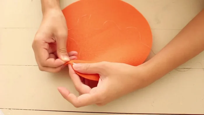 Llevar el hilo al centro de la calabaza, al centro superior y de regreso al fondo varias veces. Hacer un nudo y cortar el hilo.