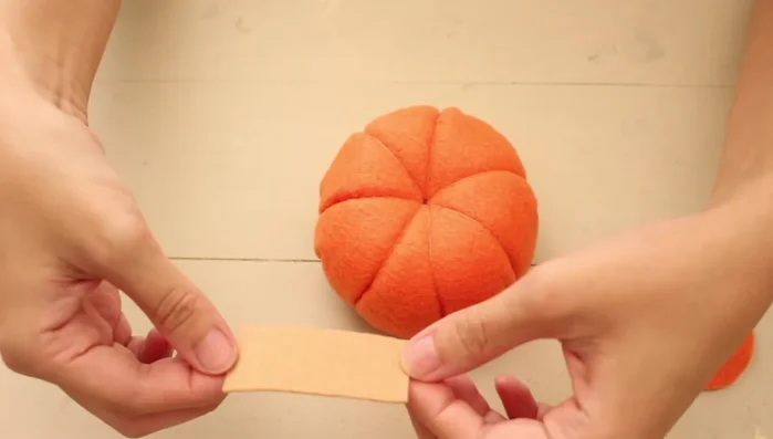 Pegar el círculo naranja en la parte inferior de la calabaza. Pegar el tallo en el centro superior junto con el círculo con púas.