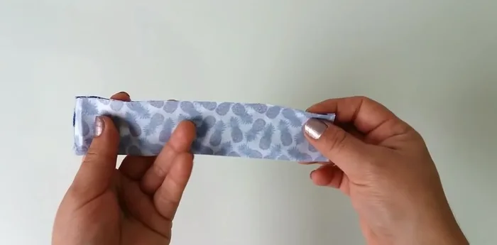 Doblar la pieza pequeña (18x8 cm) por la mitad y coser un centímetro del borde. Darle la vuelta.