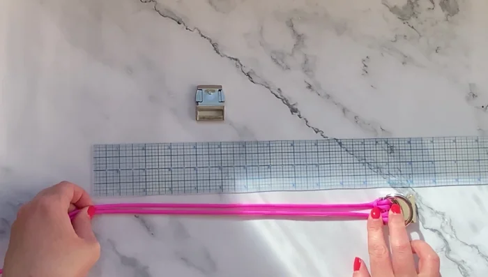 Medir y unir el cordón de inicio a la otra mitad de la hebilla: Medir 15 pulgadas (o la longitud deseada según la hoja de trucos) de cordón de inicio y unirlo a la otra mitad de la hebilla usando otro nudo de cabeza de alondra doble.